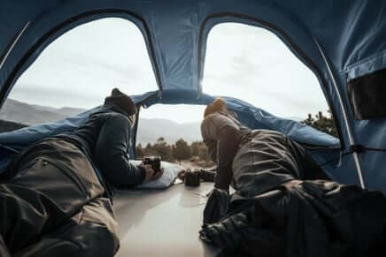 Campers lounging inside Thule Approach - Car Roof Top Tents by Thule, enjoying mountain views