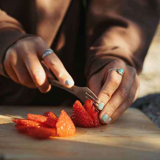 Person using SilverAnt Titanium Spork 3-In-1 Knife Fork Spoon to cut strawberries outdoors