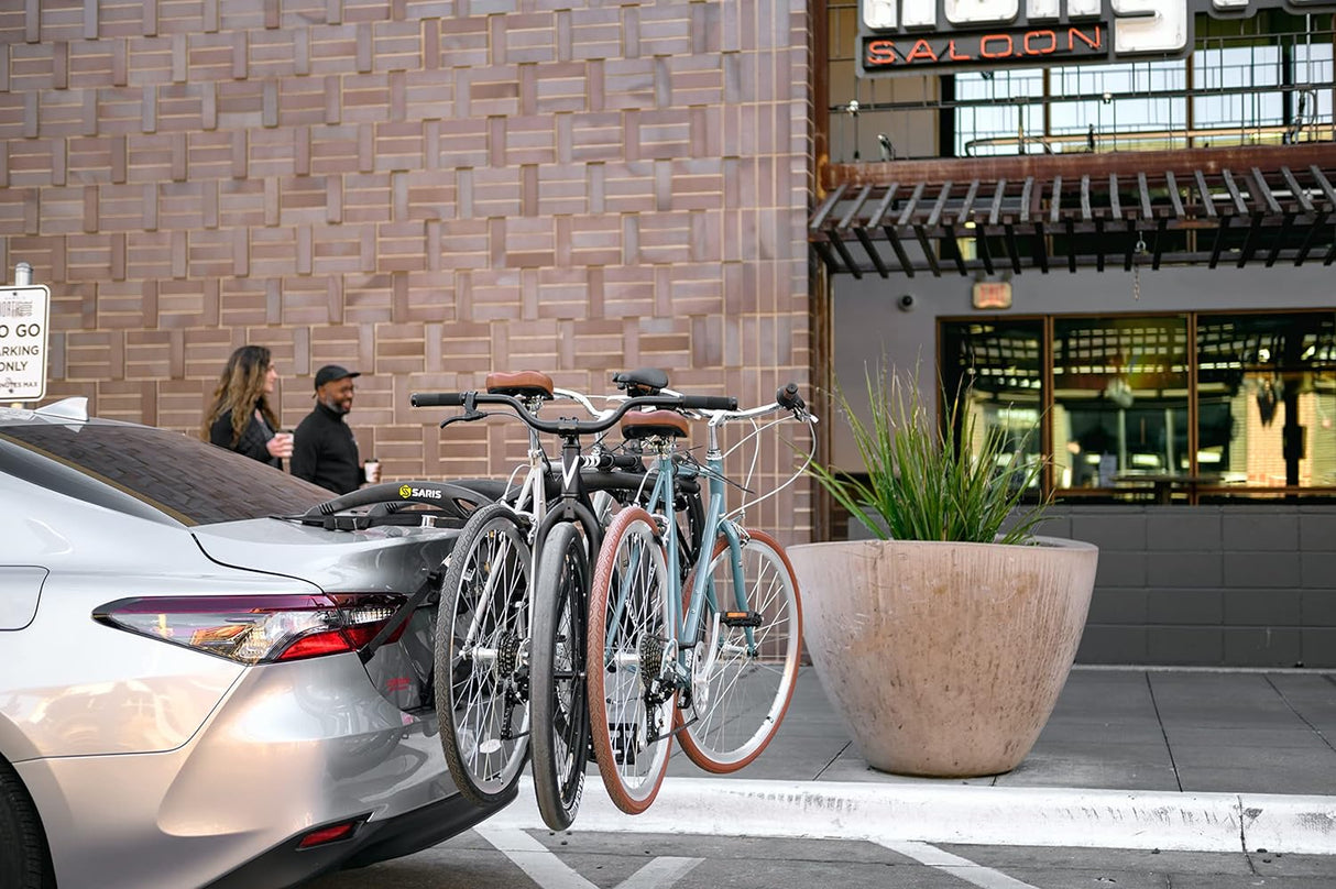 Saris Bones 3-Bike Trunk Rack mounted on a car with three bicycles in an urban setting.