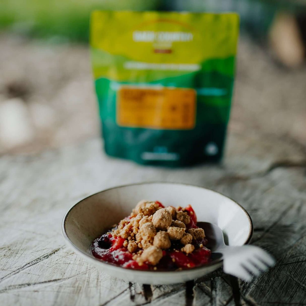 Back Country Cuisine Apple and Berry Crumble served in a bowl, with packaging in the background.