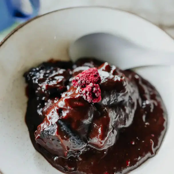 Back Country Cuisine Chocolate Brownie Pudding dessert with chocolate sauce and boysenberries in a bowl, ideal for outdoor trails.