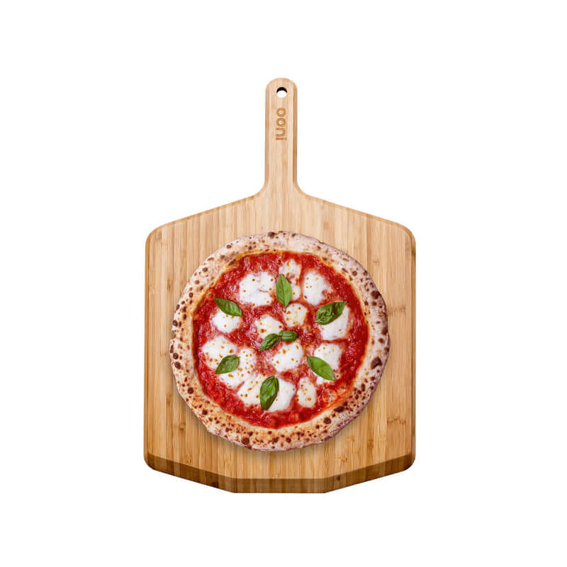 Ooni Bamboo Pizza Peel and Serving Board with margherita pizza on top, ideal for outdoor cooking and serving.