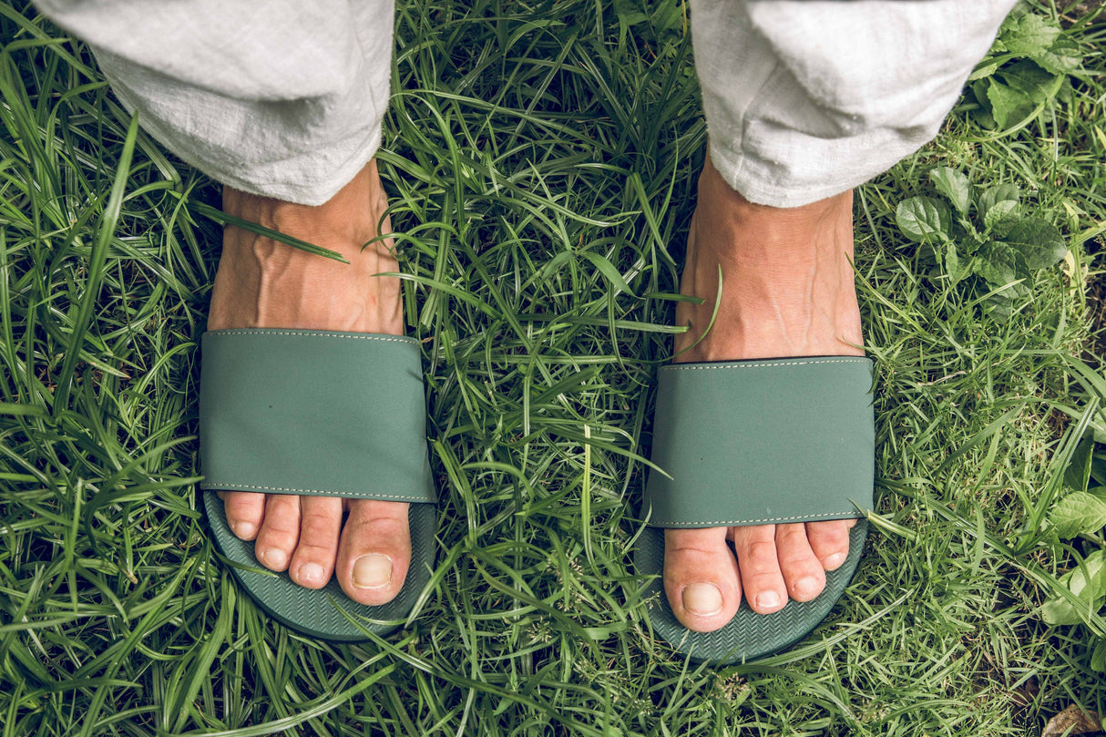 Feet wearing Indosole Slides recycled tire sole sandals on grass