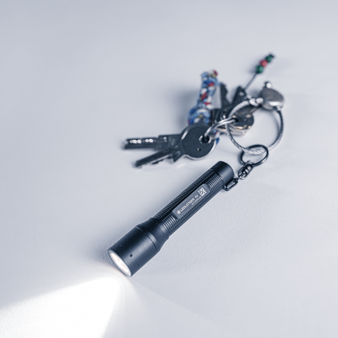 P3 tiny key flashlight with focus, keys in background, showcasing compact design and LED beam.