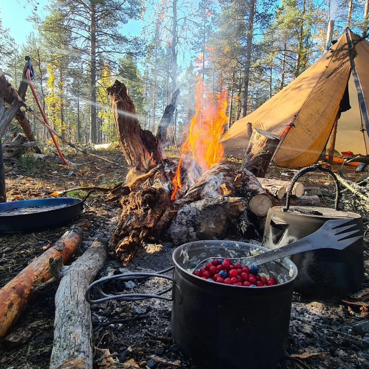 SilverAnt Titanium Spork 3-In-1 Knife Fork Spoon in outdoor campfire setting with berries and tent