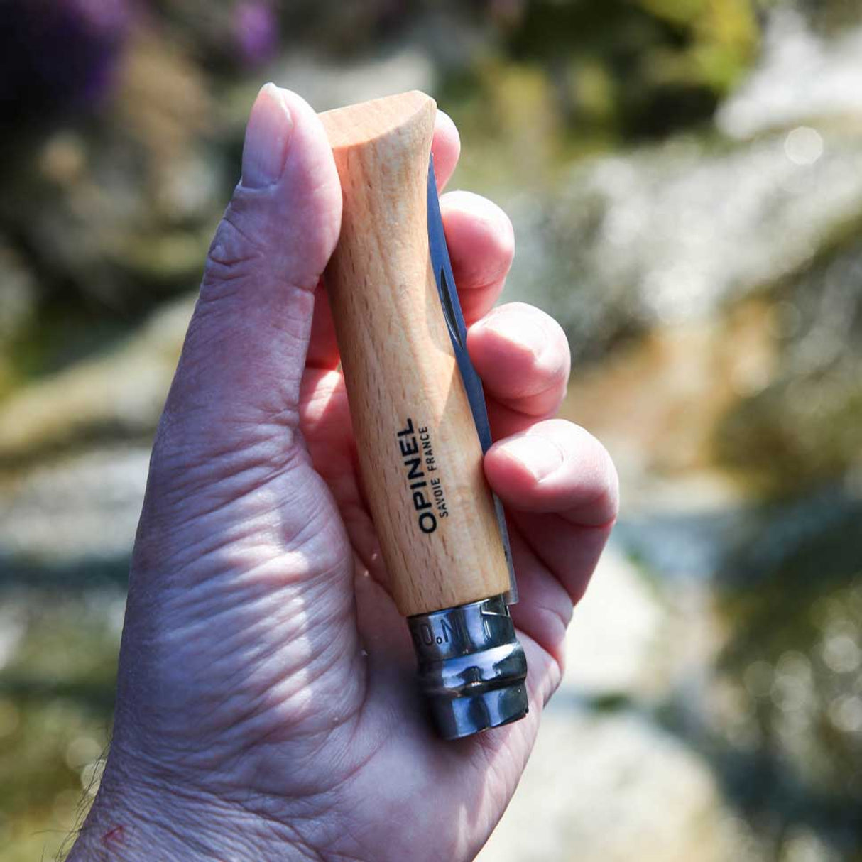 Person holding Opinel Traditional Stainless Steel Knife N°06 with Virobloc double safety ring in outdoor setting.