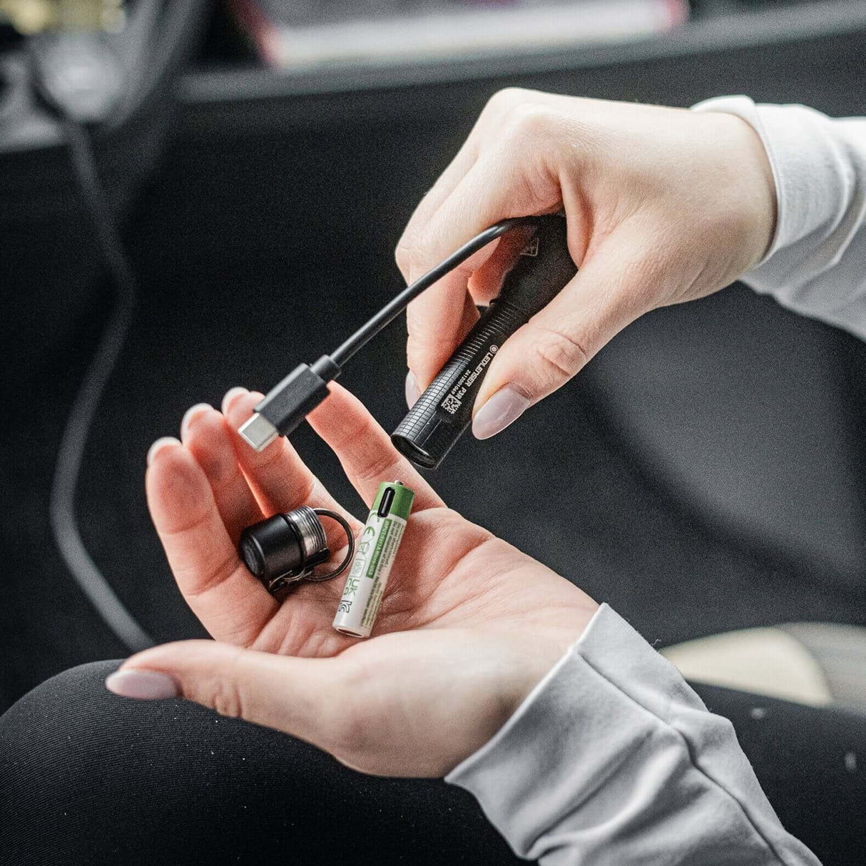 Hands holding P3R flashlight and rechargeable battery, demonstrating its everyday carry convenience.