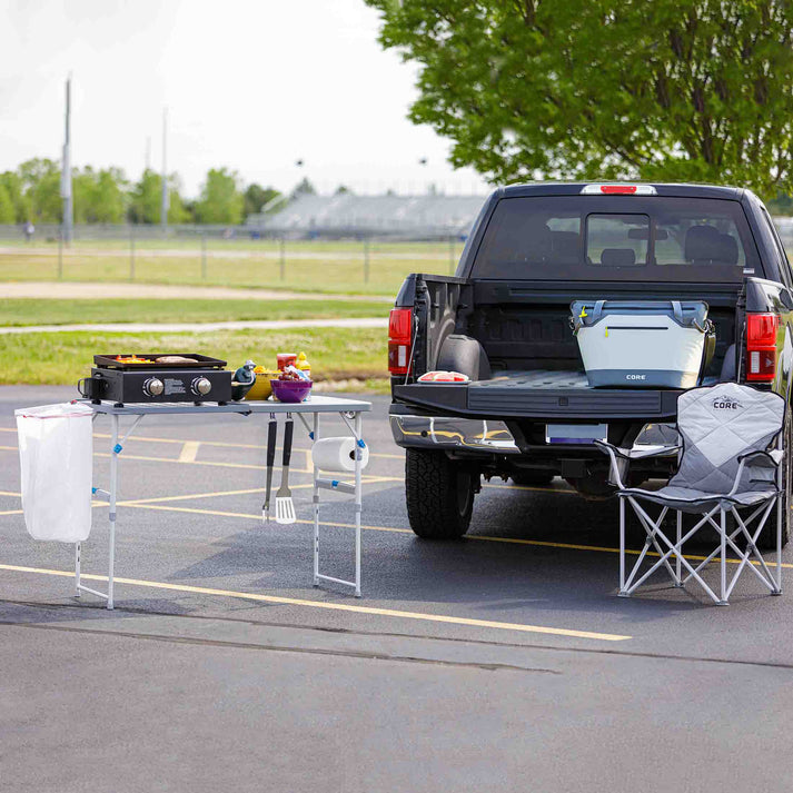 Core Equipment 4 Foot Tailgating Table — backyard tailgate setup with grill and cooler.