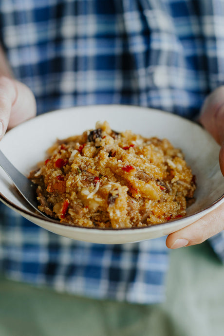 Hands holding a bowl of Back Country Cuisine Moroccan Lamb, showcasing a hearty and nourishing meal for outdoor adventures.