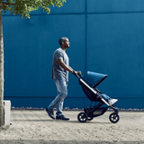 Man pushing stroller with Thule Spring Canopy - Gray Melange for comfortable rides and UV protection.