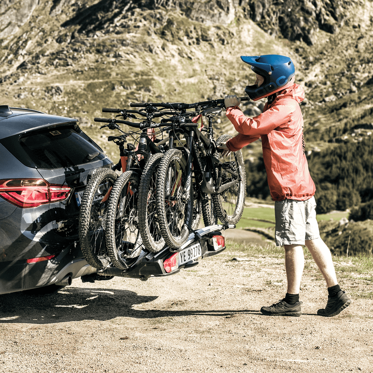 Person attaching additional bike to Thule VeloSpace XT Bike Adapter on car, enhancing capacity with Thule's durable bike rack system.