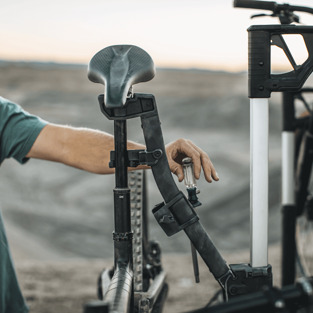 Thule Verse Bike Repair Holder in use at a trailhead, showcasing its seamless integration with Thule systems for quick bike repairs and adjustments.