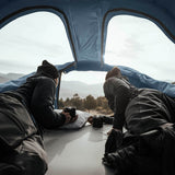 Two people relaxing inside Thule Approach - Car Roof Top Tents with scenic mountain view, showcasing Thule adventure gear.