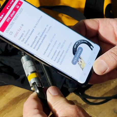Person using smartphone to access Kong I-Ovalone Carbon Auto Block carabiner data via NFC integration for safety inspection.