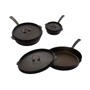 A set of three black cast iron skillets of different sizes with copper accents and lids, displayed against a white background.