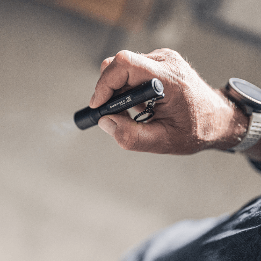 P3 tiny key flashlight held in hand showing focusable beam and sleek design.