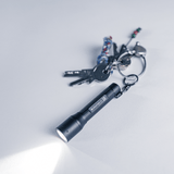 P3 tiny key flashlight with focus, keys in background, showcasing compact design and LED beam.
