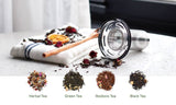 Sttoke Tea Infuser with ceramic interior and stainless mesh beside herbal, green, rooibos, and black tea varieties on a table.