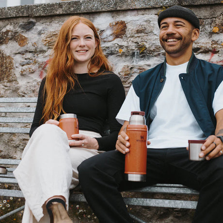 Smiling couple sitting and holding Stanley Classic Legendary Food Jar with Spork.