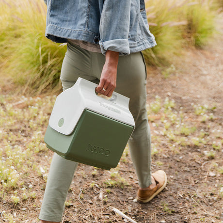 Person carrying Igloo ECOCOOL Little Playmate Cooler on an outdoor adventure, showcasing sustainable cooling technology in nature.