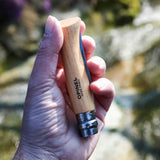 Person holding Opinel Traditional Stainless Steel Knife N°06 with Virobloc double safety ring in outdoor setting.