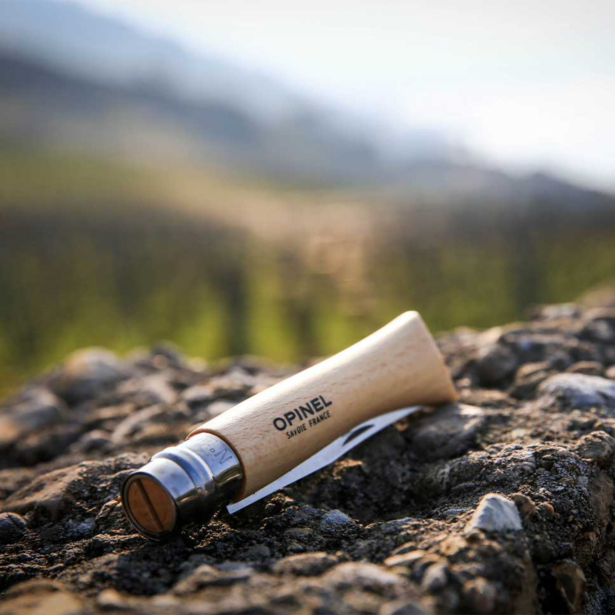 Opinel Traditional Stainless Steel Knife lying on rocky surface outdoors.