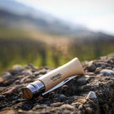 Opinel Traditional Stainless Steel Knife lying on rocky surface outdoors.