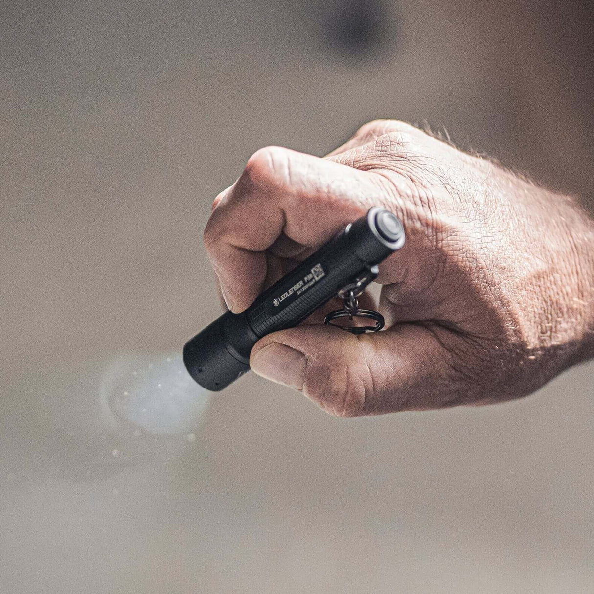 P3R compact flashlight being held, showcasing focusable light and robust design for everyday carry.