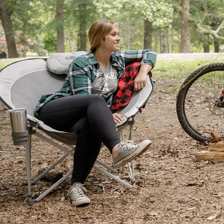 Woman sitting comfortably in Core Equipment Oversized Padded Round Chair outdoors with bike nearby
